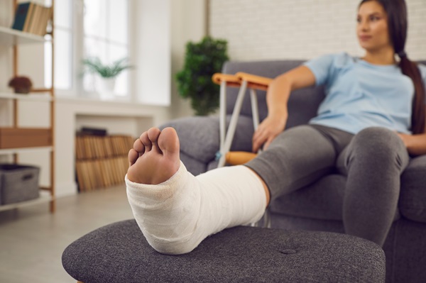 A young woman with a foot bone fracture resting on a couch at home after a serious car accident.