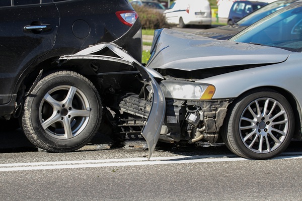 Two damaged vehicles involved in a rear-end collision on a city street.