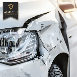 Close-up of white car with crushed front headlight and bumper damage following a car accident in Riverview