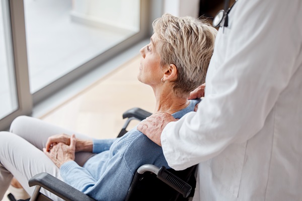 An older woman in a wheelchair looking out a window of a Florida nursing home.