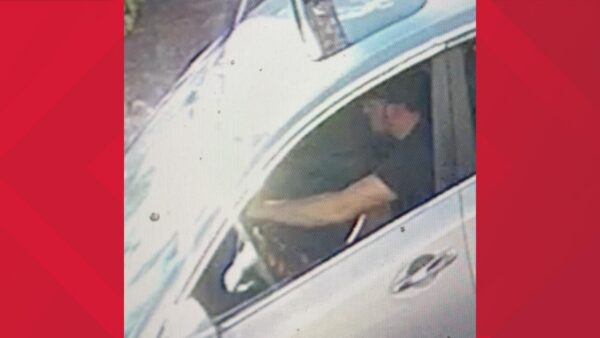 Surveillance-style image of a man sitting in the driver’s seat of a light-colored car with the window open, his arm extended inside the vehicle, connected to Temple Terrace kidnapping and sexual assault investigation.